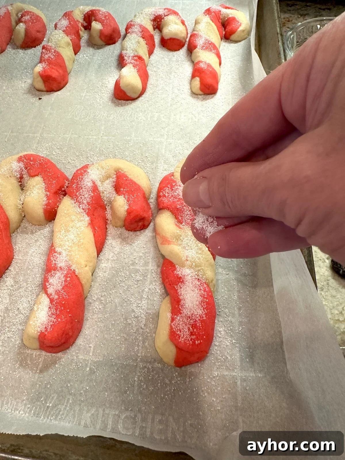 Sugar sprinkled on Christmas candy cane cookies on a baking sheet.