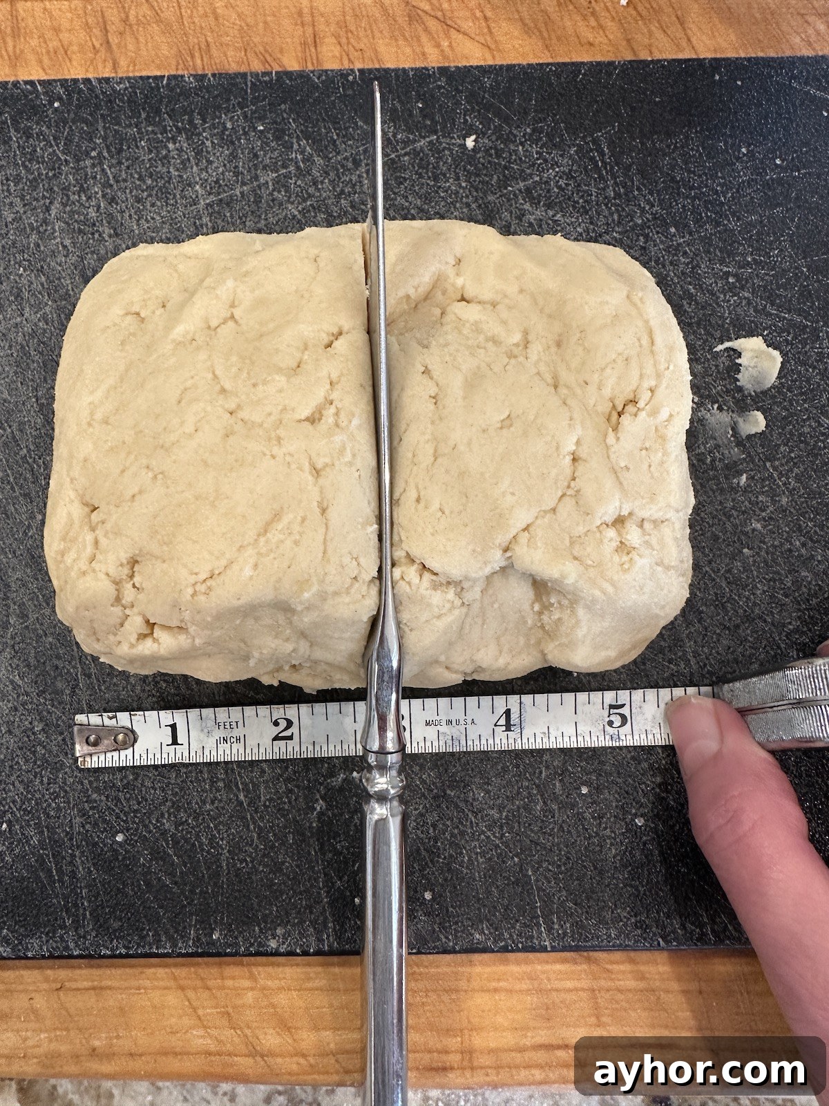 Unbaked holiday cookie dough on a cutting board with a knife and measuring stick.