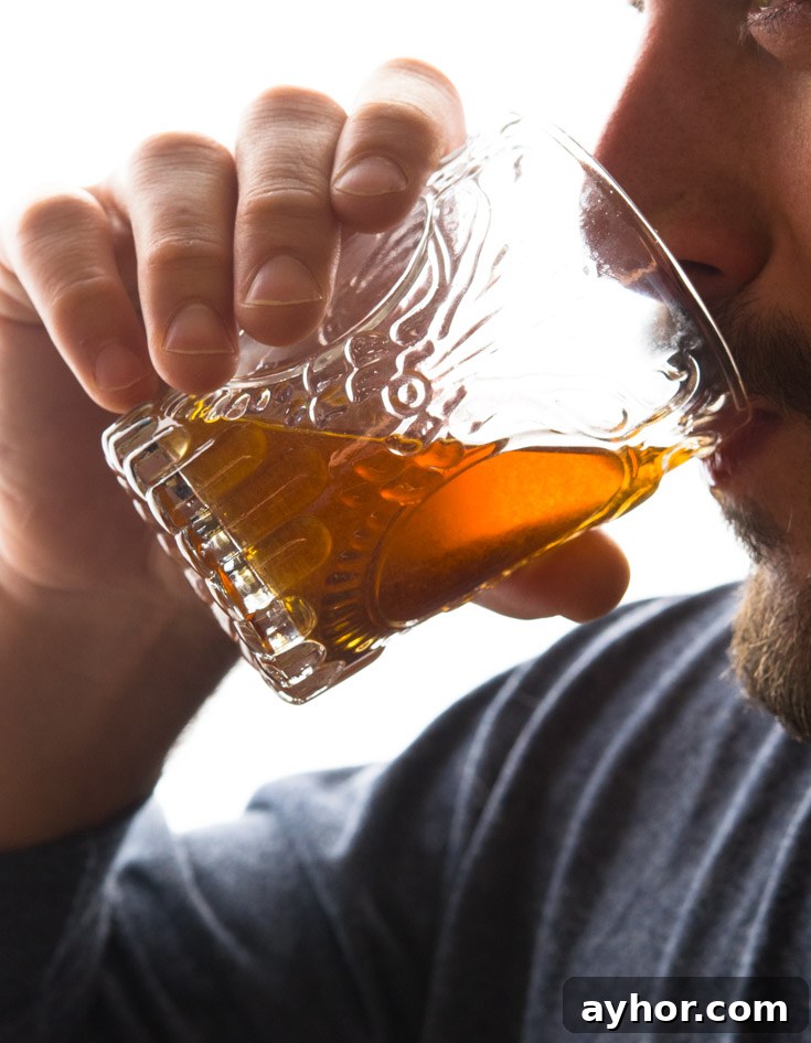 Spice up the holidays with apple pie moonshine, the fiery beverage of outlaws domesticated by a touch of grandma’s apple pie. A unique gift for adult pals. #moonshine #applepiemoonshine Man drinking Apple Pie Moonshine