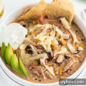 Creamy White Chicken Chili with Homestyle Flavor 7 A bowl of crockpot white chicken chili topped with cheese, avocado, sour cream, and tortilla chips.