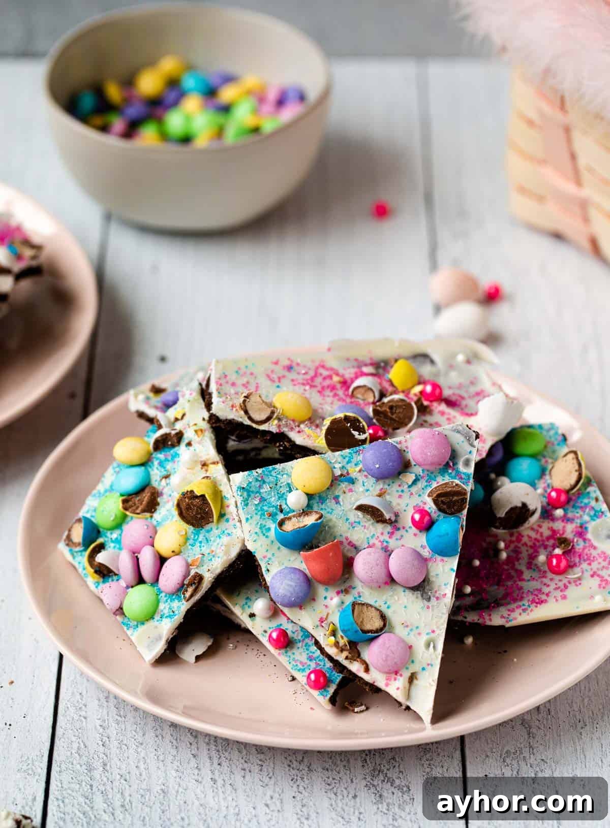 Easter Chocolate Bark Recipe: Spring Candy with Colorful Eggs 2 broken pieces of candy bark on a pink plate