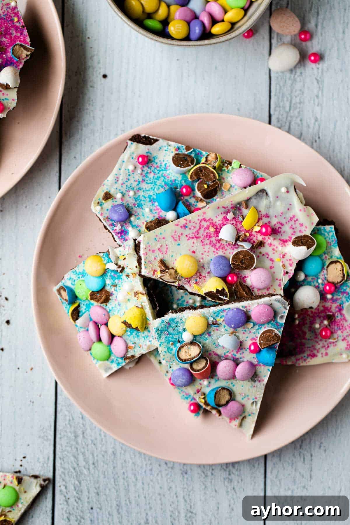 Easter Chocolate Bark Recipe: Spring Candy with Colorful Eggs 10 close up of pieces of recipe on a pink plate