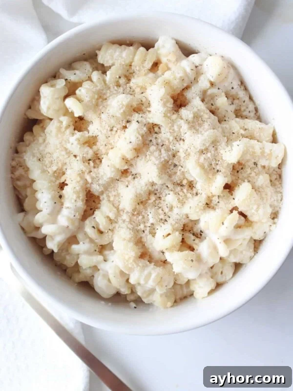 High-Protein Baked Ziti Recipe for Muscle & Meal Prep 13 A bowl full of cottage cheese pasta sauce on chickpea pasta and topped with parmesan cheese and black pepper in a white bowl.
