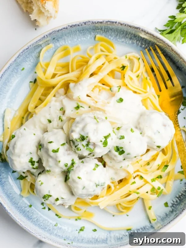 High-Protein Baked Ziti Recipe for Muscle & Meal Prep 14 Alfredo meatballs on a plate with pasta and garnished with parsley.