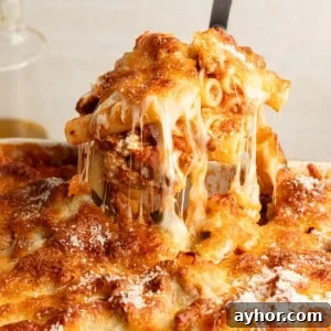 High-Protein Baked Ziti Recipe for Muscle & Meal Prep 16 A hot scoop of high protein baked ziti being lifted from the baking dish with lots of cheese.