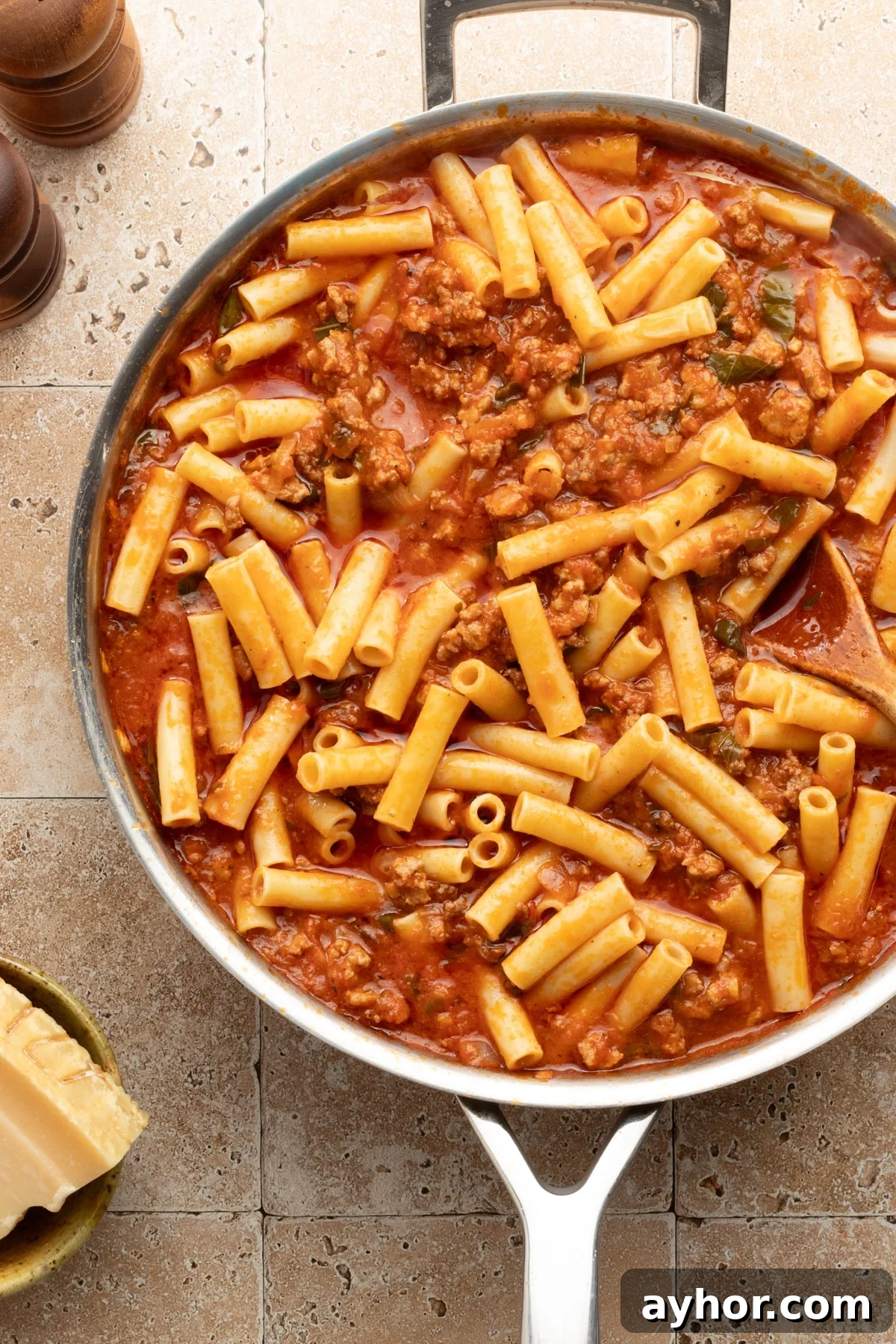 High-Protein Baked Ziti Recipe for Muscle & Meal Prep 7 Meat sauce with cooked ziti in a large skillet.