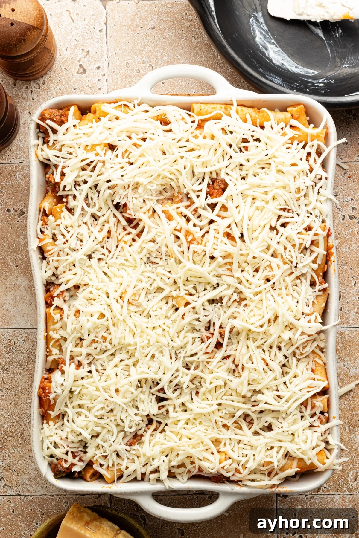 High-Protein Baked Ziti Recipe for Muscle & Meal Prep 9 Shredded mozzarella cheese on top of high protein baked ziti ready for the oven.