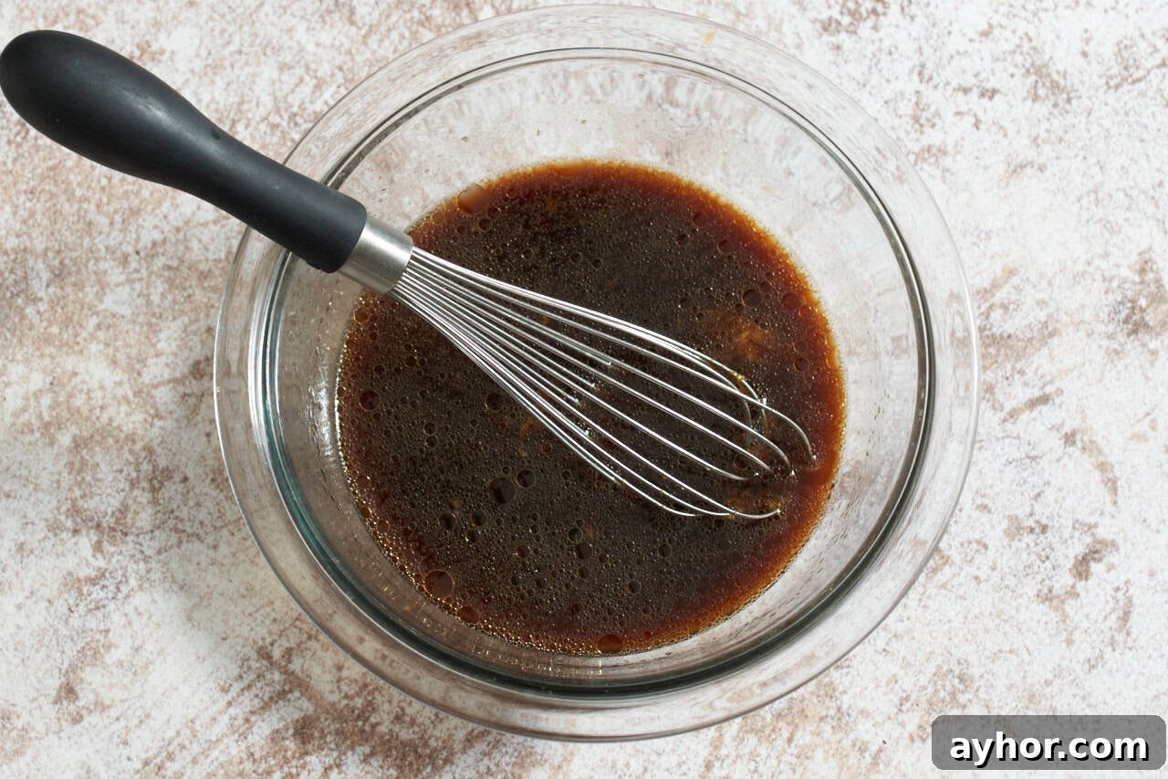 A bowl of stir fry sauce with a whisk in it.