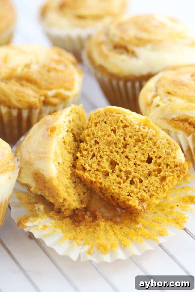 Pumpkin muffins cooling on a wire rack with one opened and cut in half.