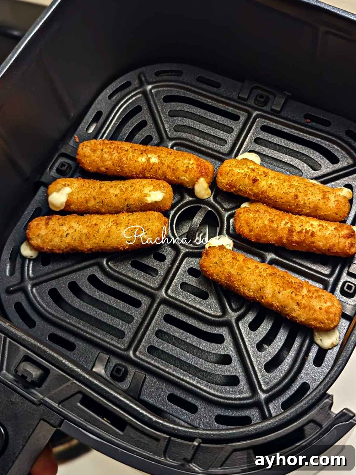 Crispy golden mozzarella sticks after air frying in air fryer basket.