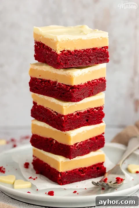 A stack of 5 red velvet millionaire brownies set on two stacked plates with a fork on the side.