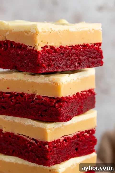 A close up of 4 red velvet millionaire brownies in a stack set against a mottled light background.