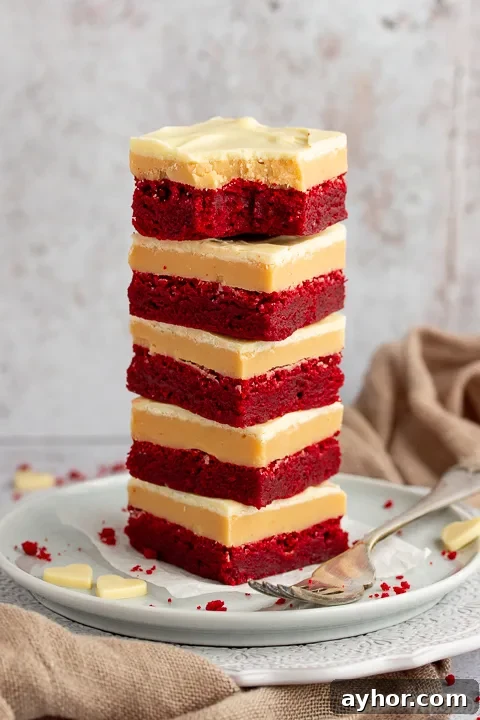 A stack of 5 red velvet millionaire brownies set on two stacked plates with a fork on the side.