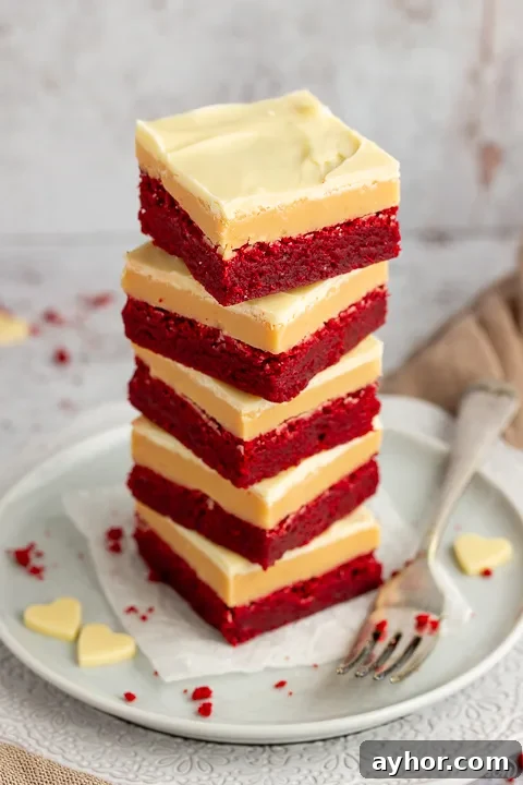 A stack of 5 red velvet millionaire brownies set on two stacked plates with a fork on the side.