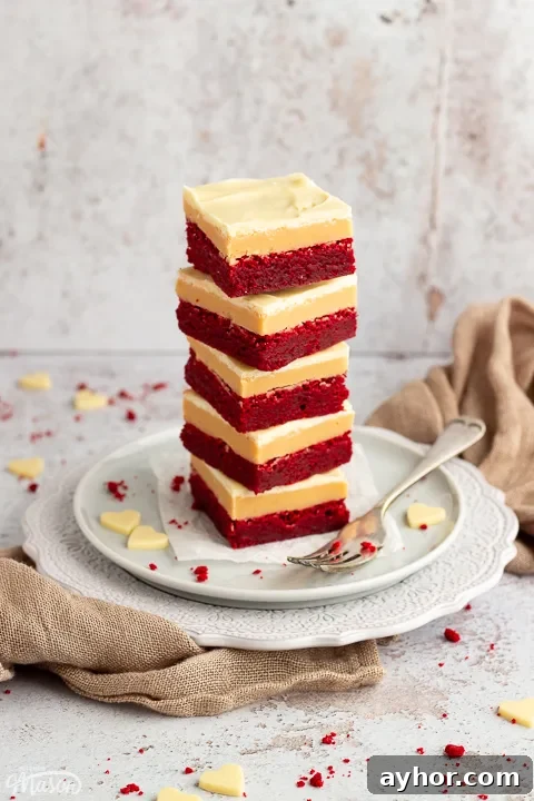 A stack of 5 red velvet millionaire brownies set on two stacked plates with a fork on the side.