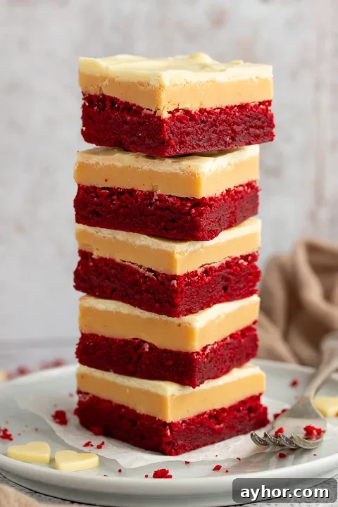 A stack of 5 red velvet millionaire brownies set on two stacked plates with a fork on the side.