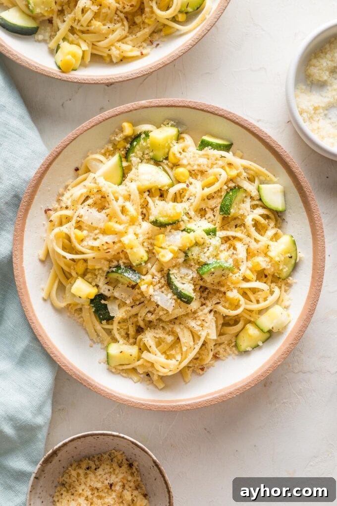 Shallow pasta bowl filled with a helping of pasta with zucchini, corn, and toasted garlicky breadcrumbs.
