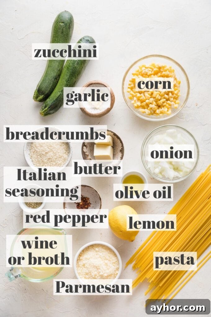 Overhead image of zucchini, corn, garlic, breadcrumbs, onion, olive oil, butter, Italian seasoning, red pepper flakes, white wine, Parmesan, lemon, and pasta arranged in prep bowls.