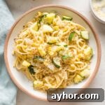Shallow pasta bowl filled with a helping of pasta with zucchini, corn, and toasted garlicky breadcrumbs.