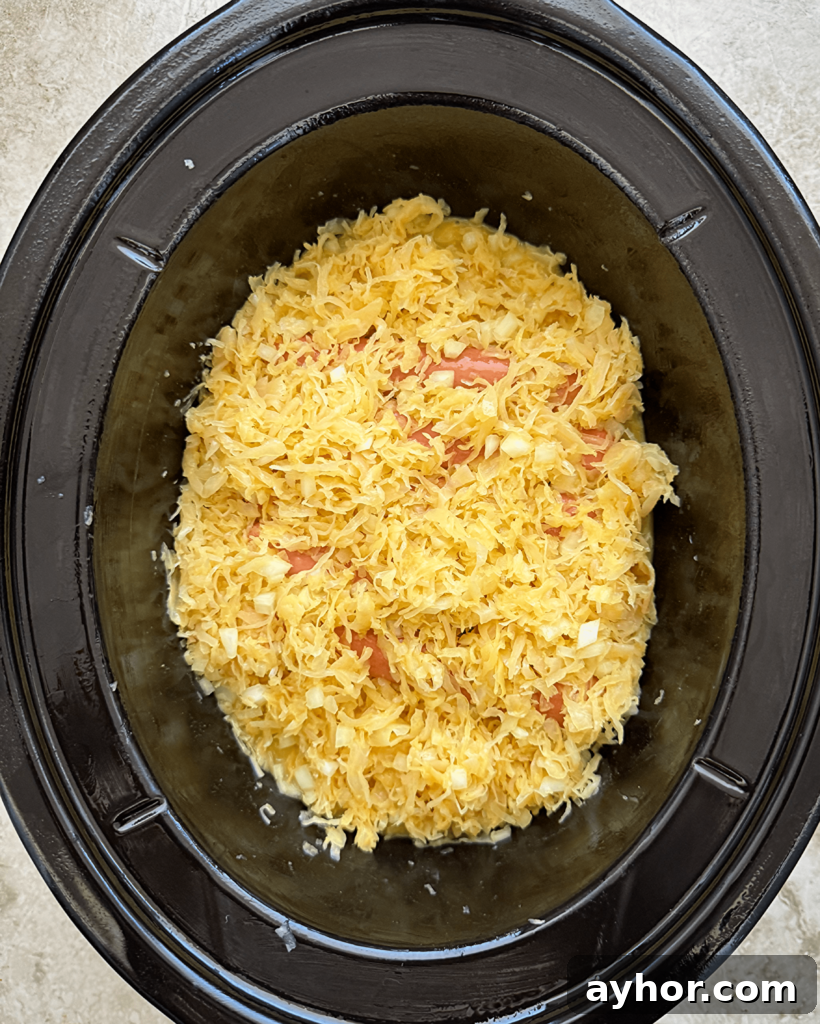 overhead shot of uncooked hot dogs covered in sauerkraut a black slow cooker