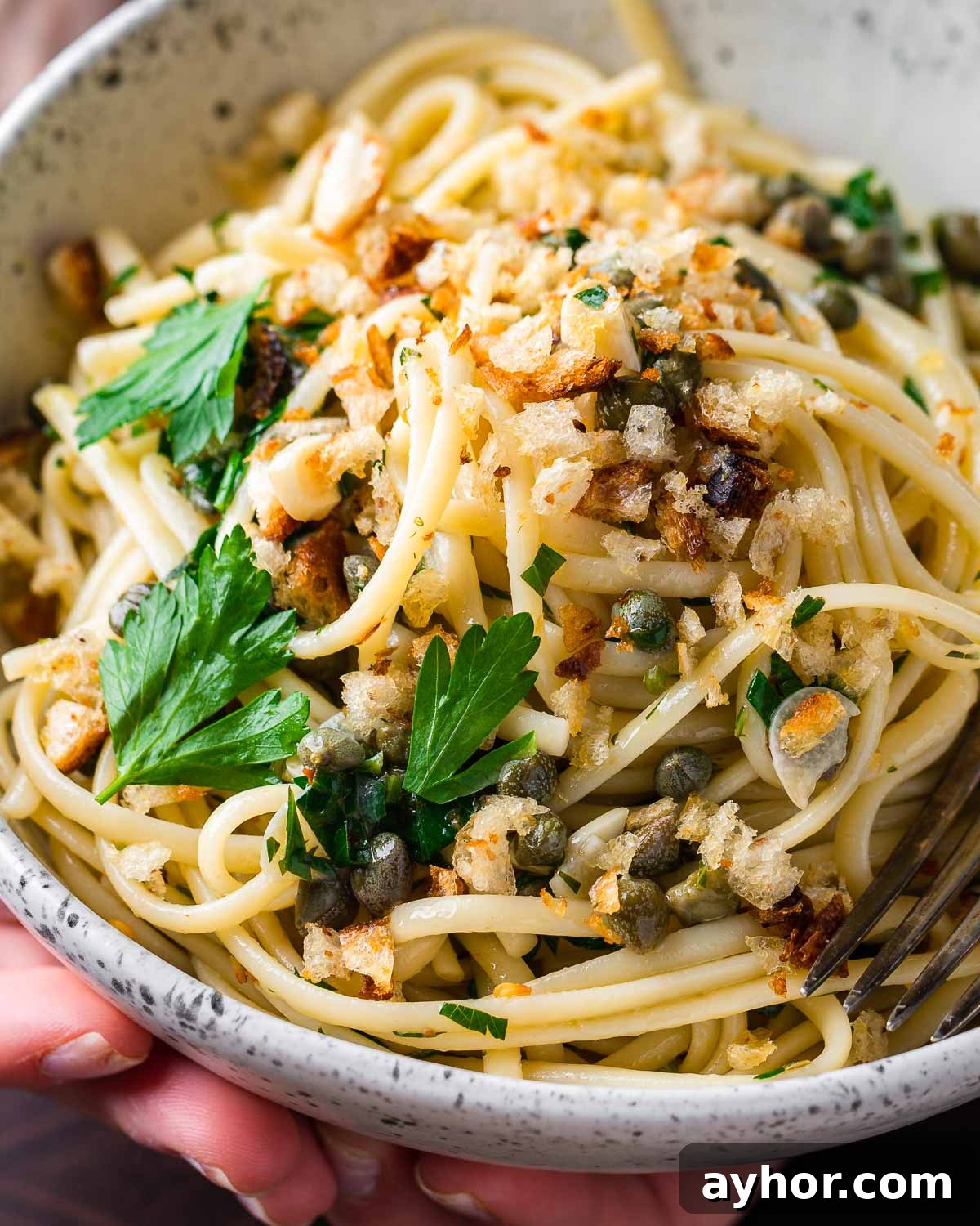 Podcast 33: Essential Kitchen Tools Every Cook Should Own 2 Hands holding lemon caper pasta in white bowl.