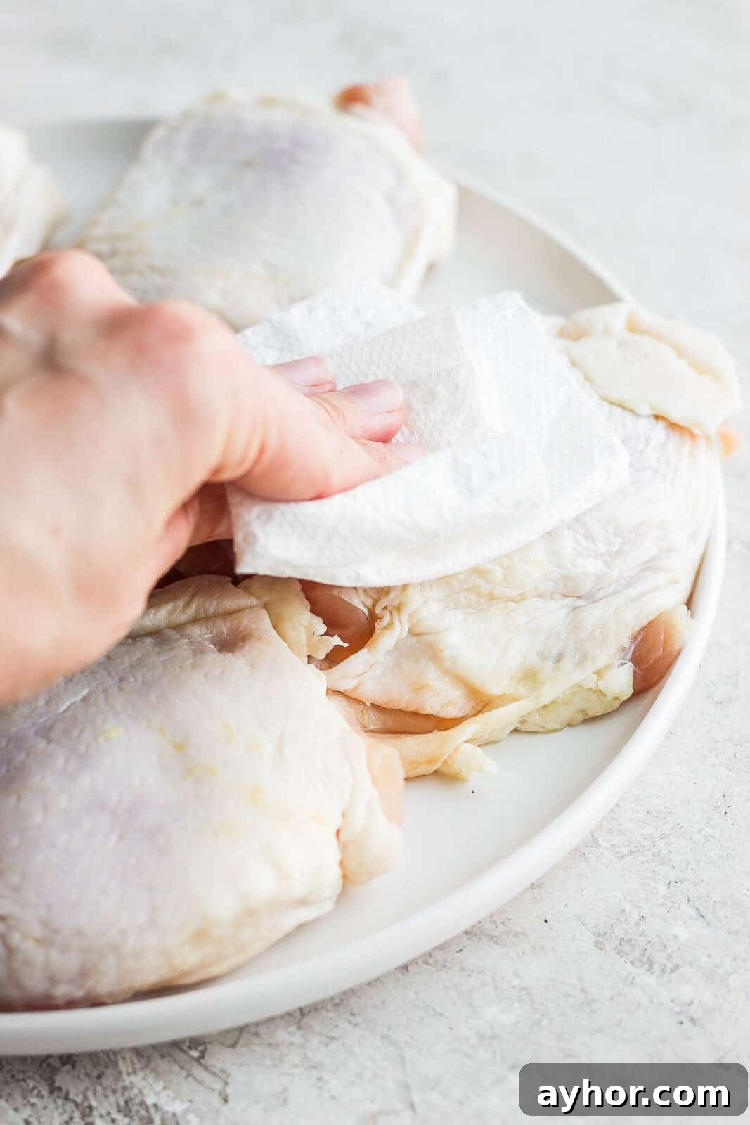 Patting chicken dry with a paper towel.