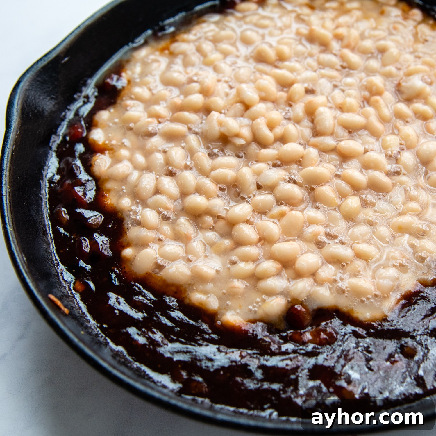 canned beans being added to the sauce.