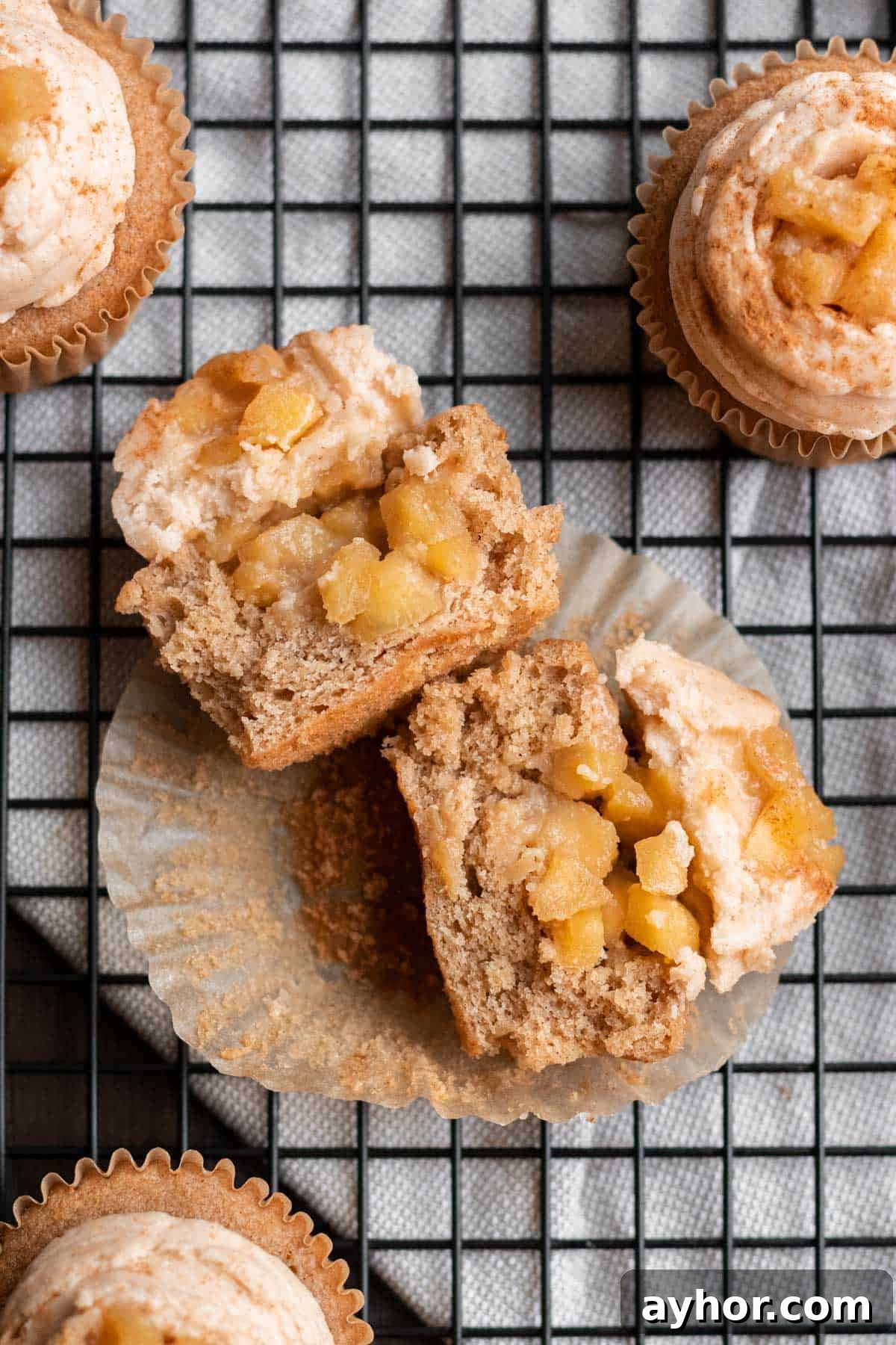 apple pie cupcake cut in half with apple pie filling in center and frosting and apple pie filling on top