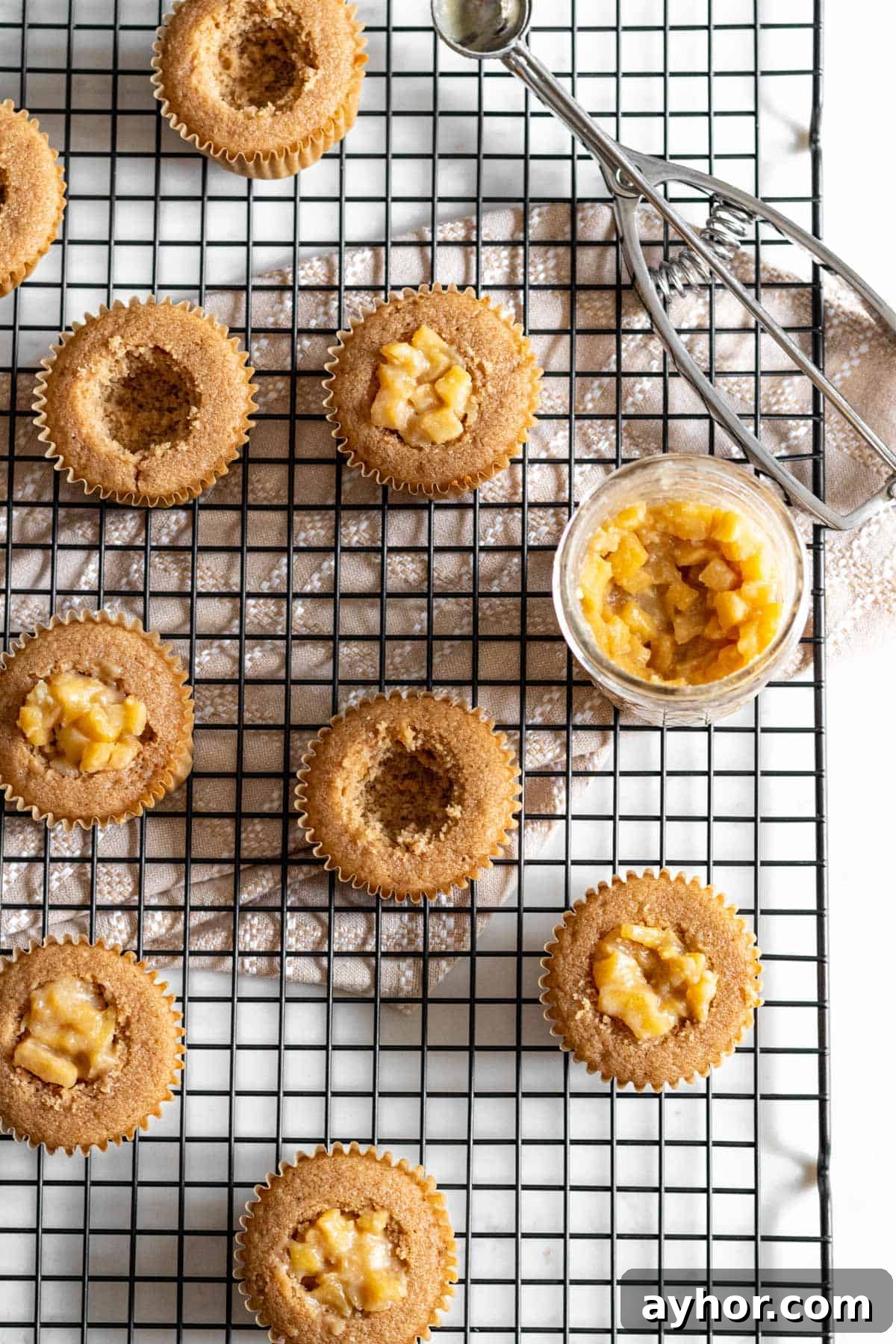 cupcakes on cooling rack with center of cake cut out and apple pie filling in half the cupcakes