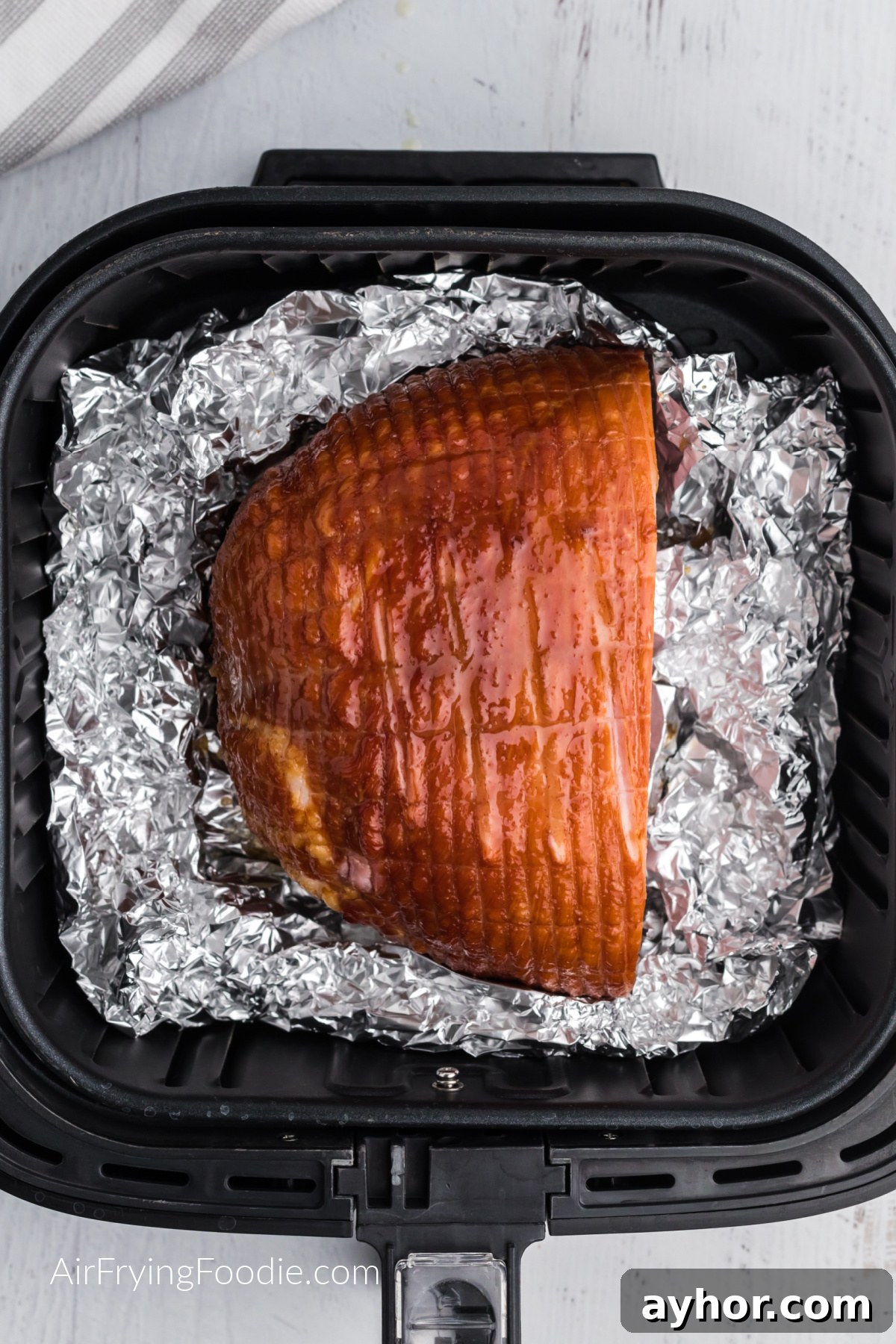 ham in air fryer basket laying on foil, ready to be served.