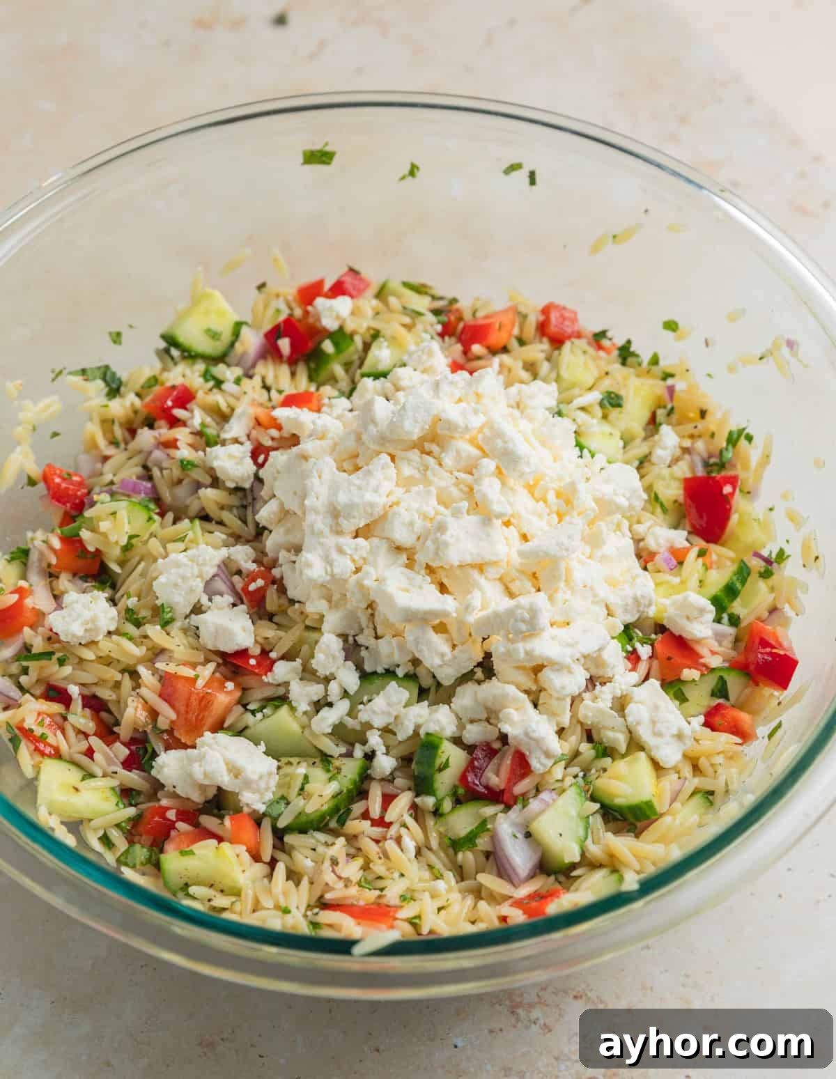 Feta added over top of salad mixture in bowl.