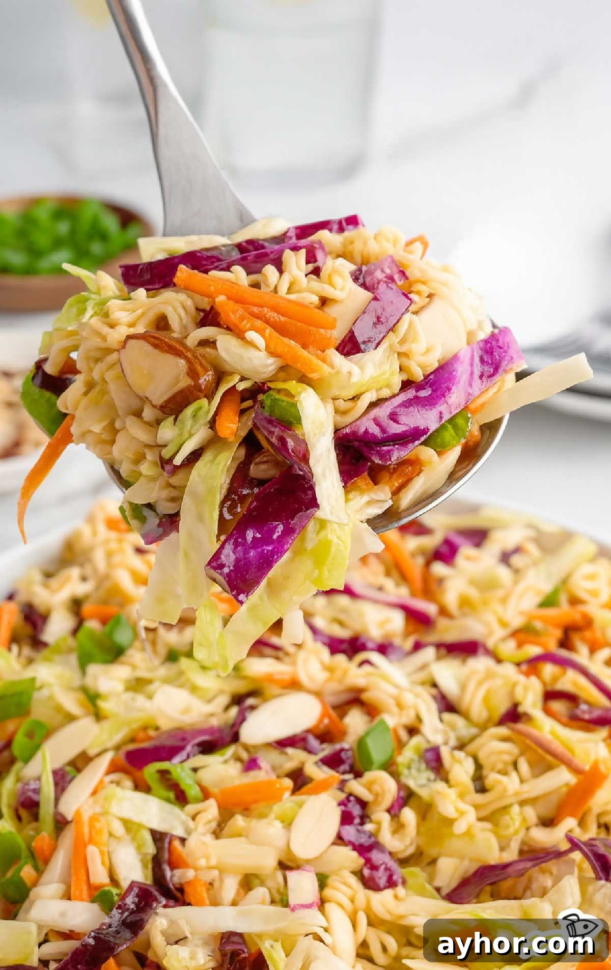 Crunchy Japanese Ramen Noodle Salad with Sesame-Ginger Dressing 6 Spoonful of ramen noodle salad showing crunchy vegetables and toasted noodles held above serving bowl