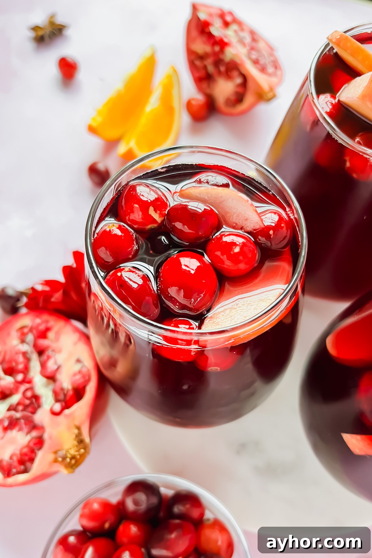 Festive Thanksgiving Sangria Recipe for Holiday Gatherings 2 glass full of thanksgiving sangria garnished with cranberries and apple slices.