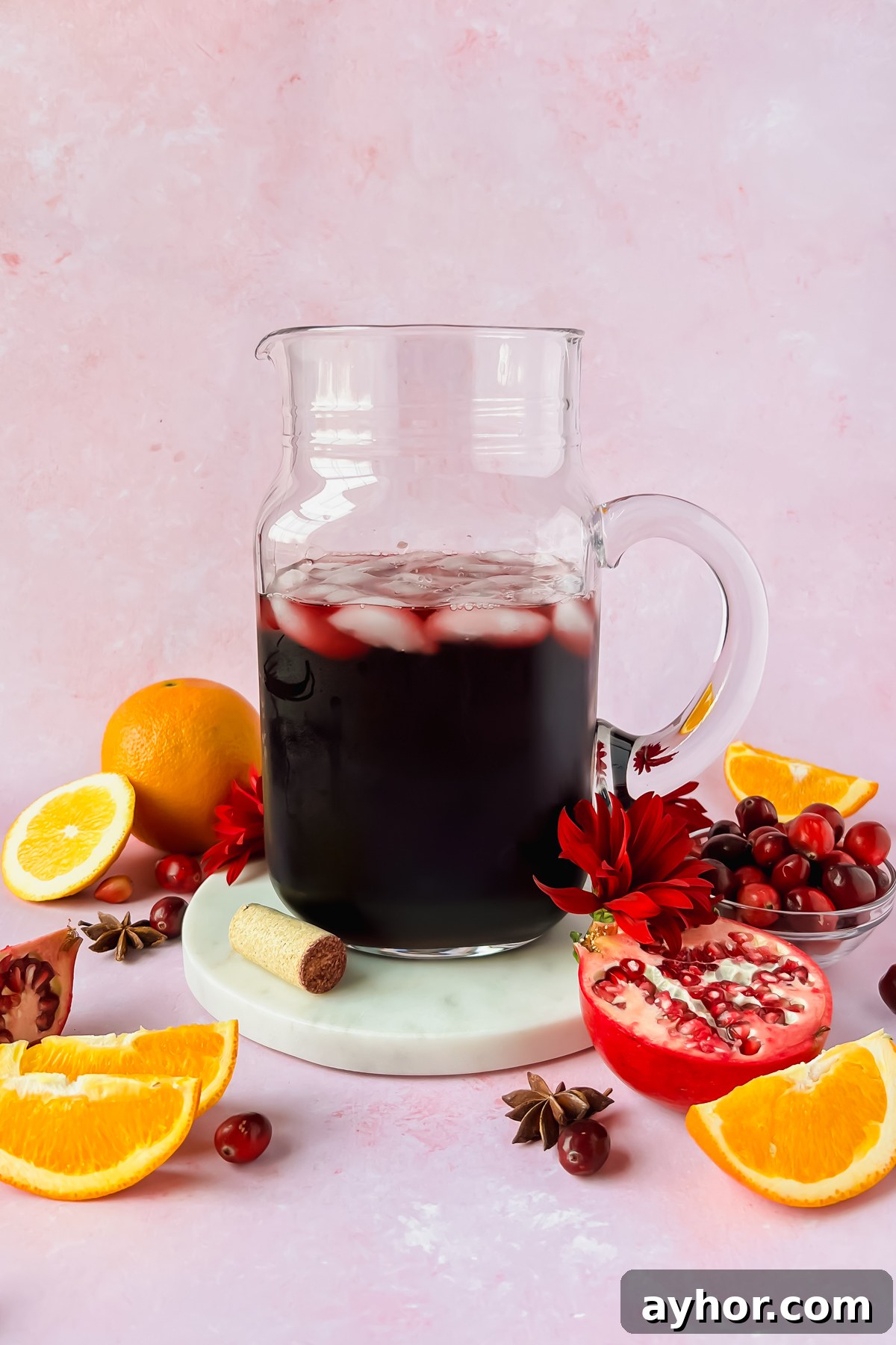 Festive Thanksgiving Sangria Recipe for Holiday Gatherings 6 pitcher full of thanksgiving sangria surrounded by orange slices, cranberries, and pomegranate.