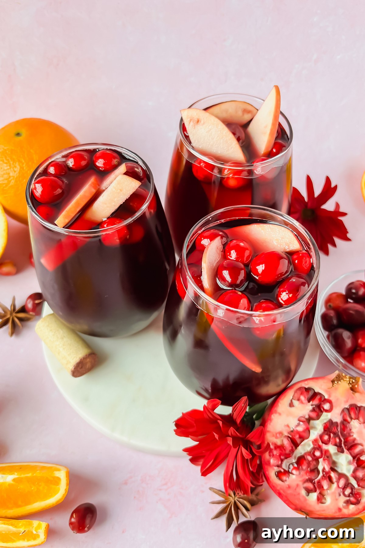 Festive Thanksgiving Sangria Recipe for Holiday Gatherings 8 three glasses of thanksgiving sangria garnished with cranberries and apple slices.