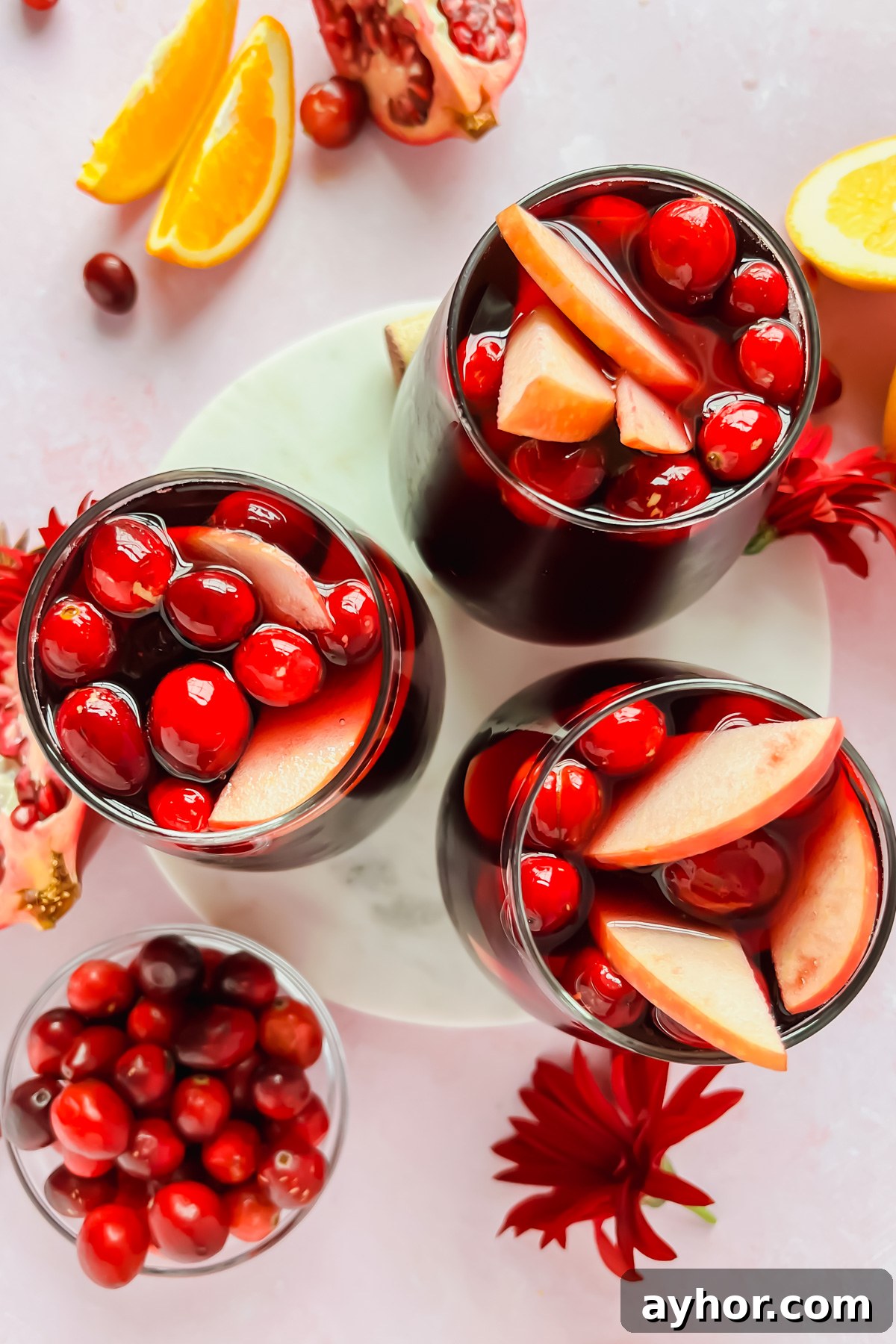 Festive Thanksgiving Sangria Recipe for Holiday Gatherings 9 three glasses of thanksgiving sangria garnished with cranberries and apple slices.