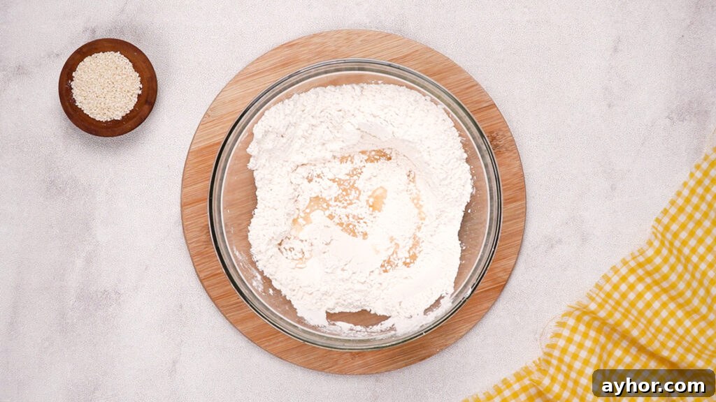 The flour mixture in the glass bowl is partially combined, showing the first stage of blending the dry ingredients for the gluten-free cracker dough.