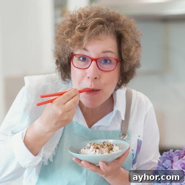 Beth Lee holding red chopsticks and eating rice out of blue bowl.