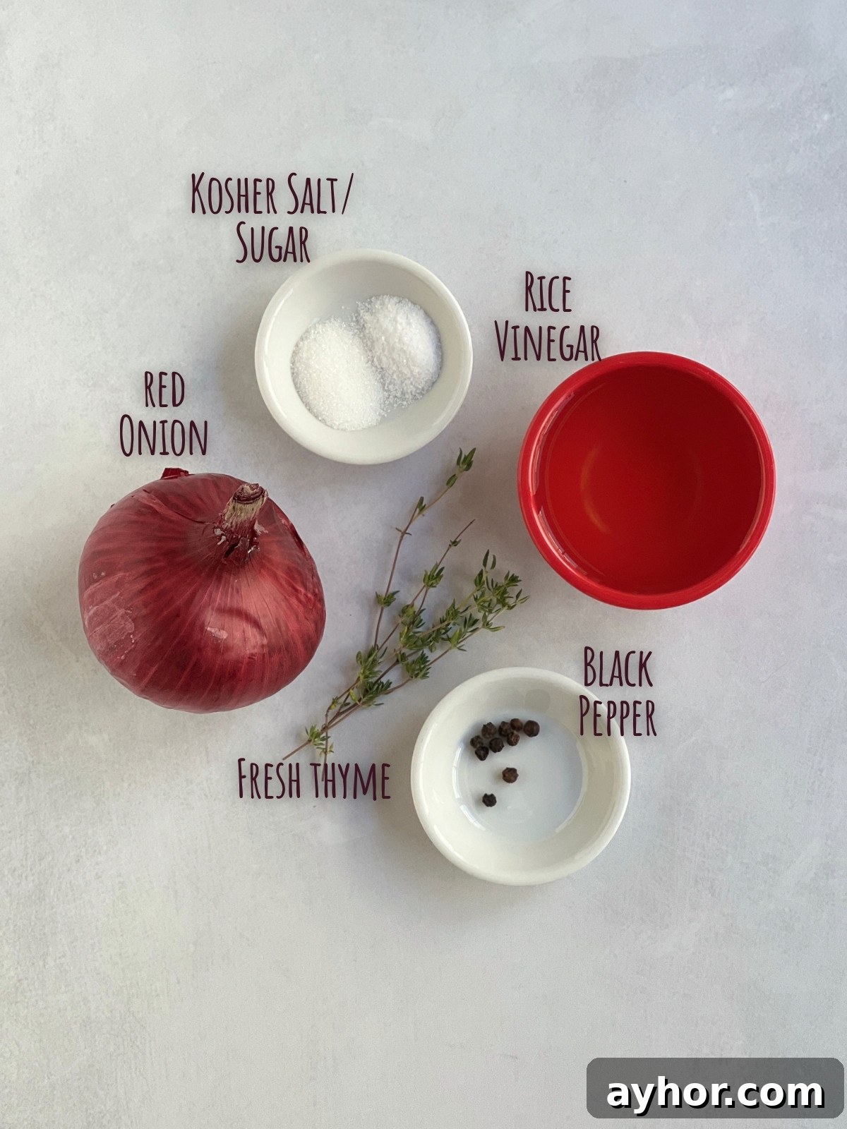 Ingredients shot for pickled red onions showing a whole red onion, salt, sugar, rice vinegar and thyme and black peppercorns.