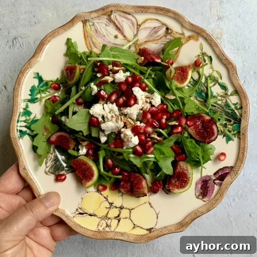 Arugula and Fig Salad on a plate with a hand holding the plate.