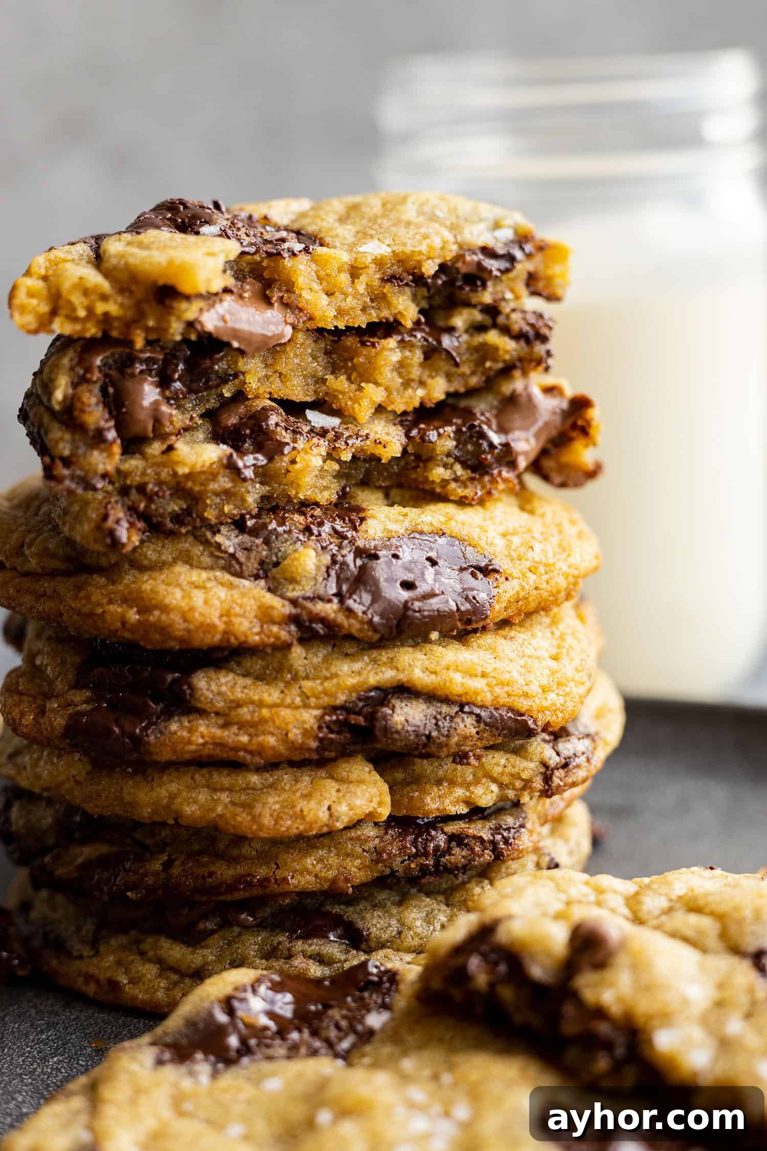 A stack of cookies. Some are broken in half to show the melty chocolate inside. 