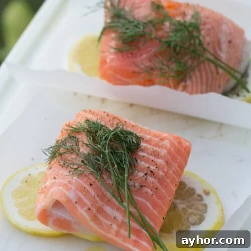 Salmon on parchment paper squares with lemon and fresh dill