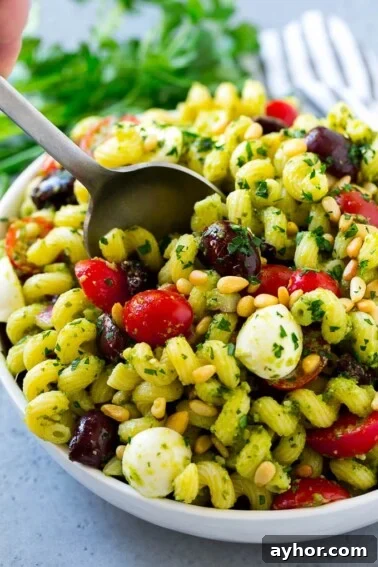 Pesto pasta salad with cherry tomatoes, olives, mozzarella balls, pine nuts and red onion.