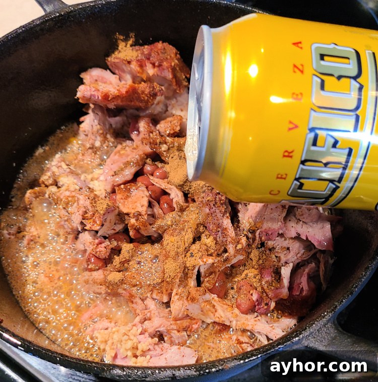 Pacifico beer being poured into dutch oven for pulled pork chili