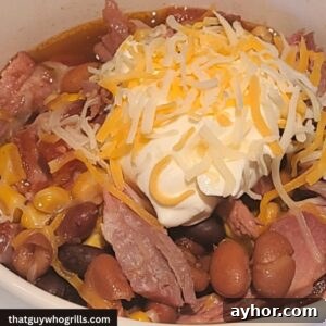 Leftover Pulled Pork Chili served with sour cream and cheese in a white bowl