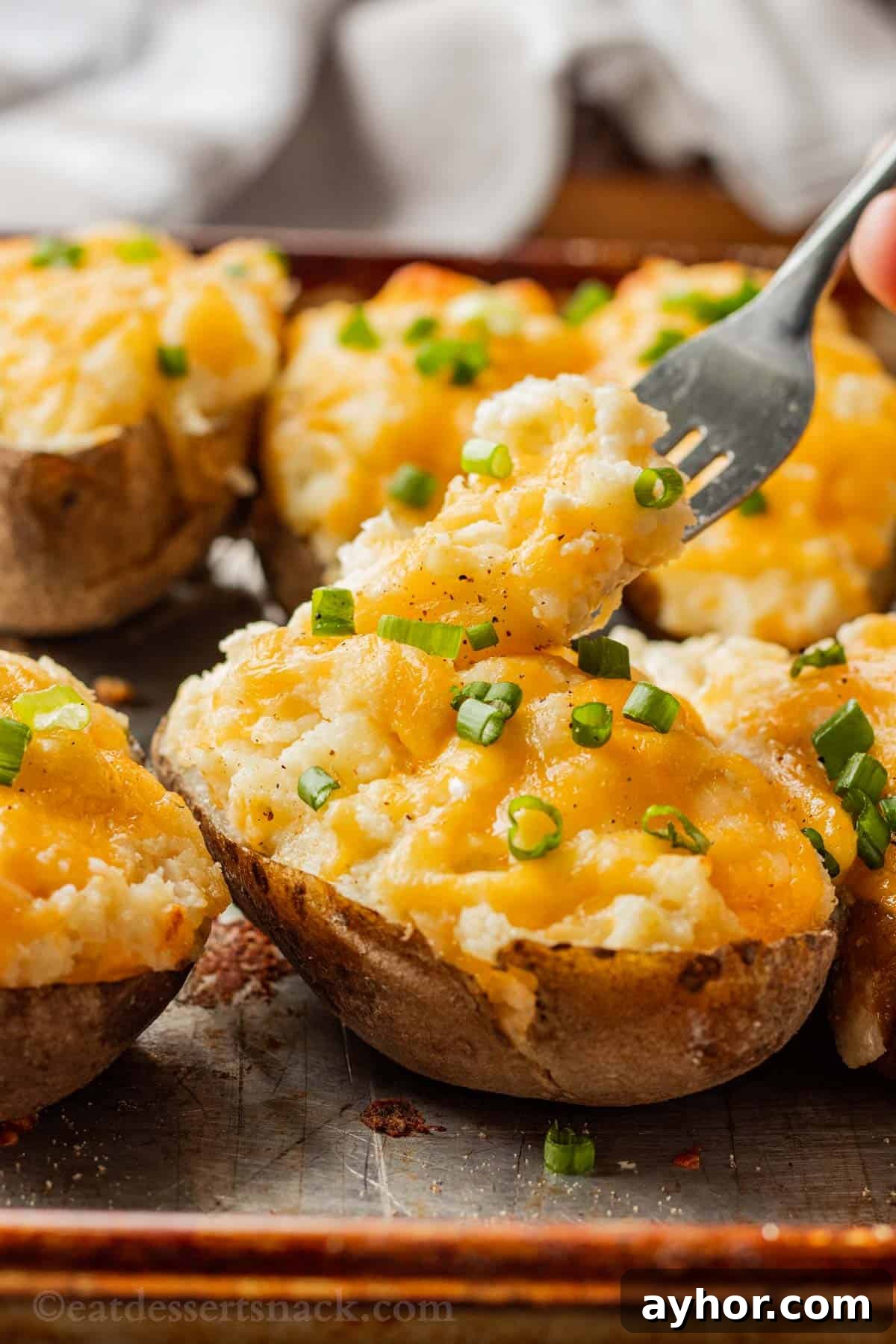Boursin Twice baked potatoes covered in melted cheese with fork above.