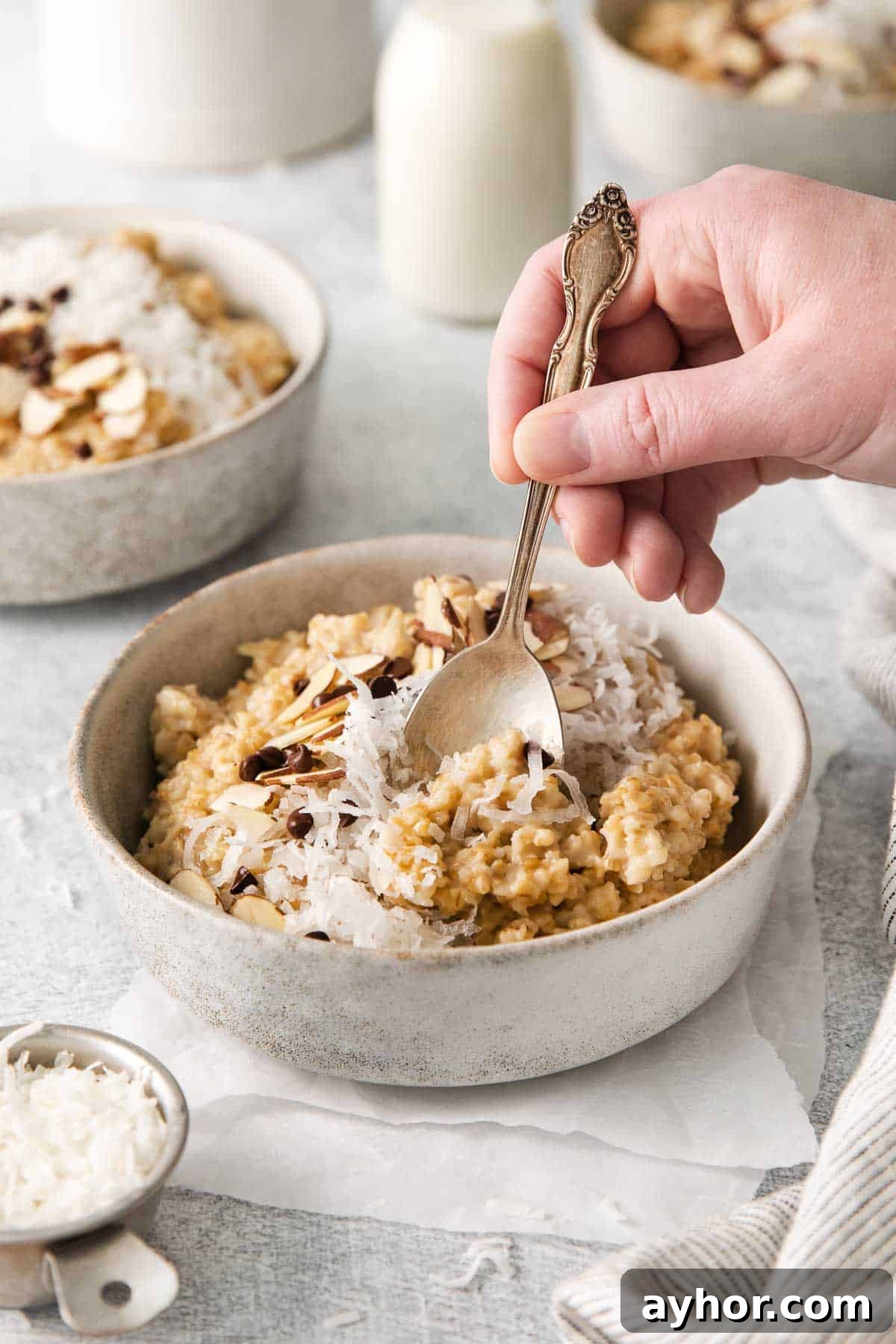 A bowl of steel cut oats, and a hand scooping up a bite with a spoon