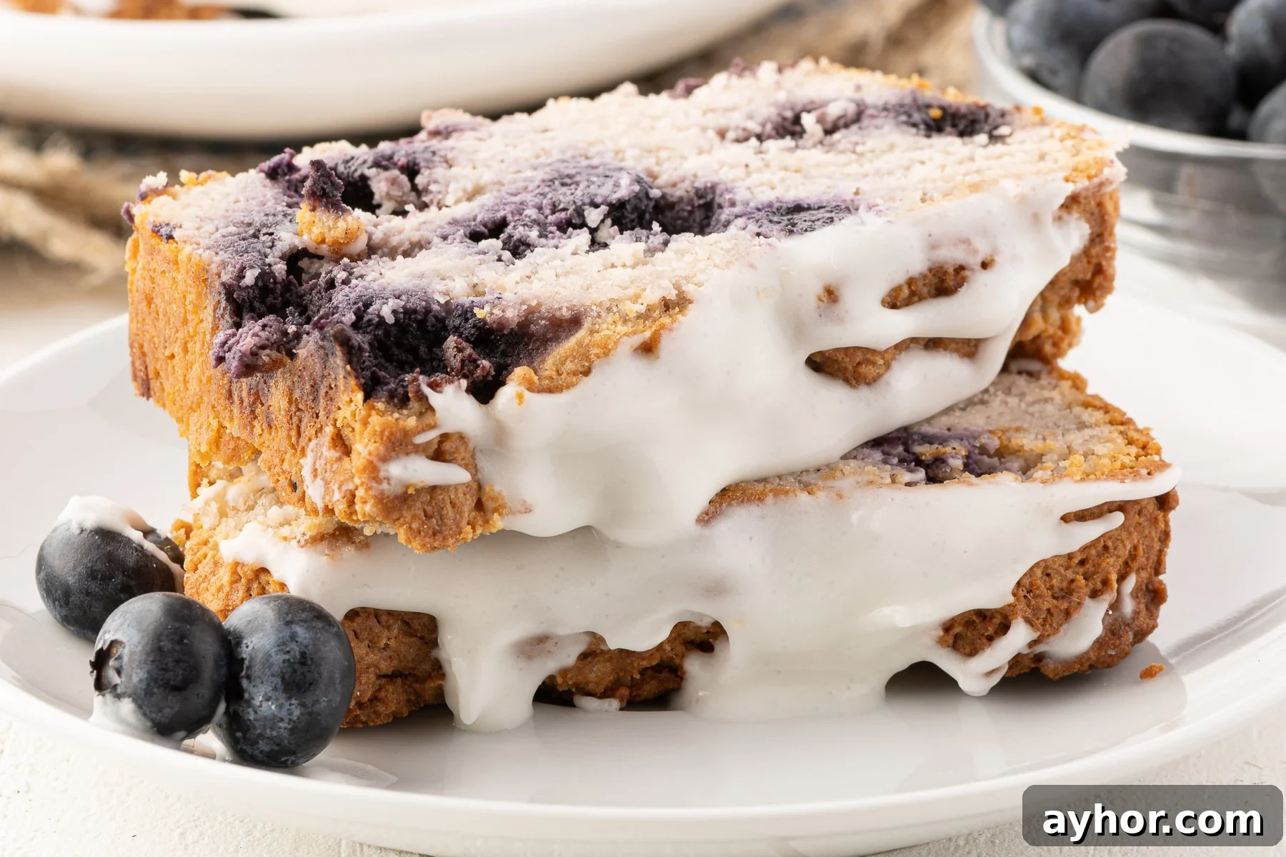Low-Carb Keto Blueberry Bread with Zesty Lemon Drizzle 2 Two slices of keto blueberry bread on a small plate, with fresh blueberries on the side.