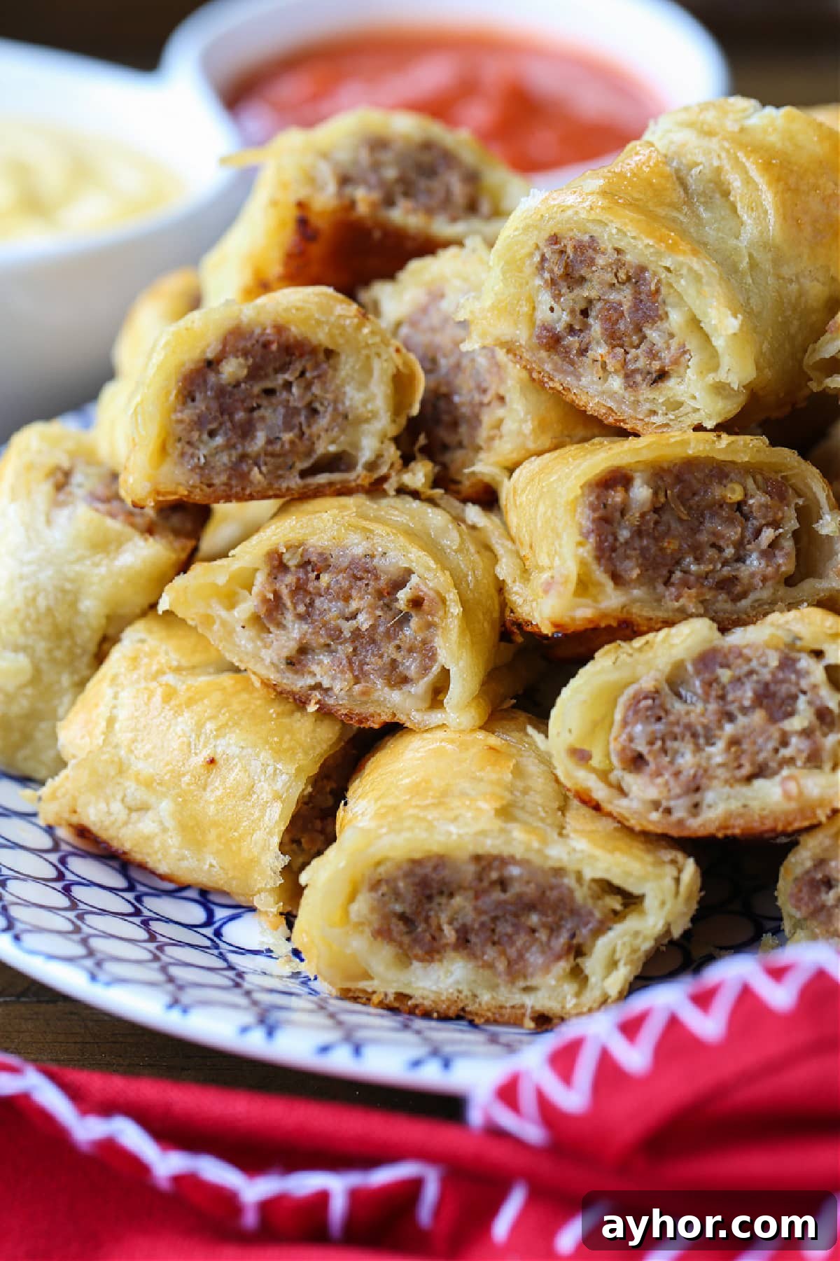 Everyone loves Puff Pastry Sausage Rolls! A buttery, flaky crust with a cheesy sausage filling. Perfect for holidays, parties and game days! puff pastry sausage rolls stacked on plate