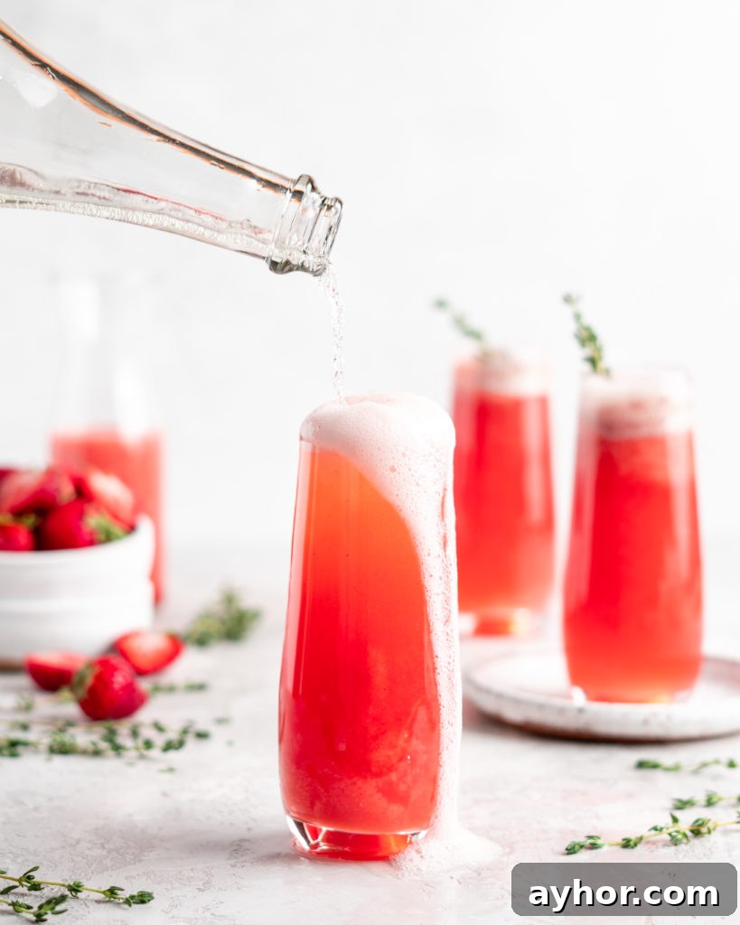 Bright red strawberry guava juice is mixed with sparkling rose wine in stemless champagne glasses to make Strawberry Guava Mimosa